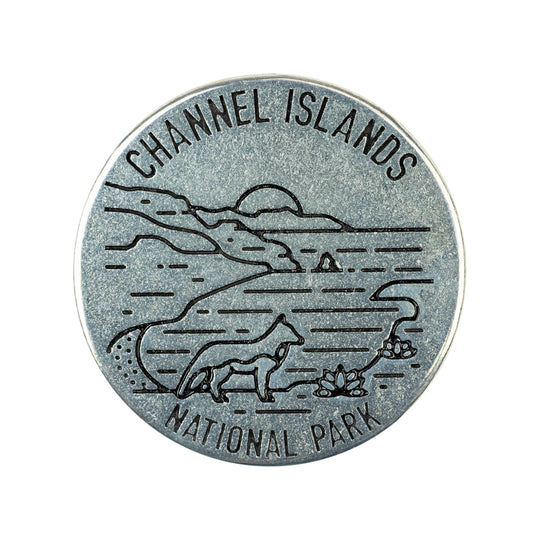 A round silver-toned metal token engraved with a landscape scene and the words &