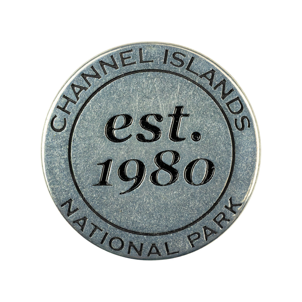 A round metal token featuring embossed text that reads 'CHANNEL ISLANDS est. 1980 NATIONAL PARK' on a plain white background.