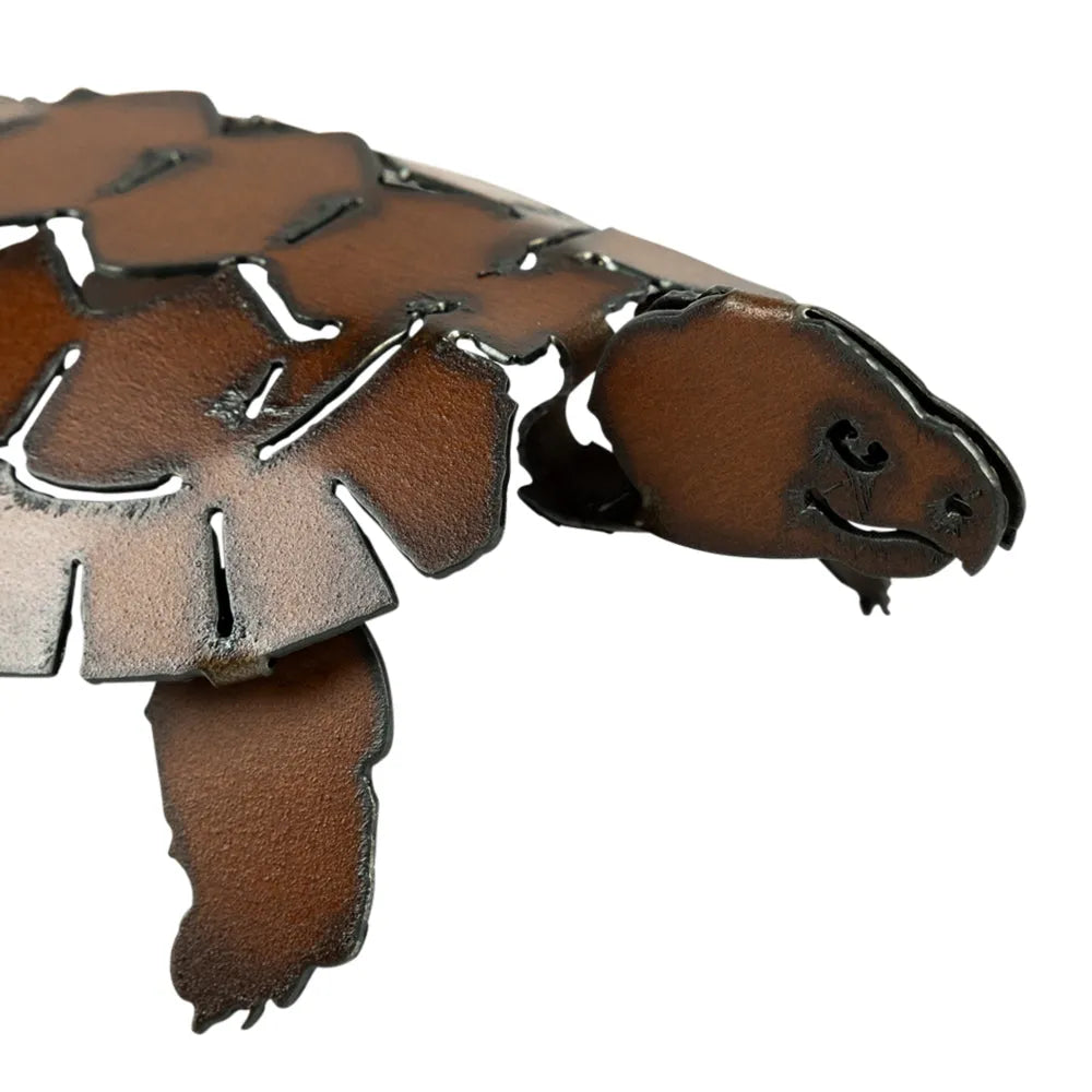 Close-up of a brown patina metal turtle with cut-out design on a white background
