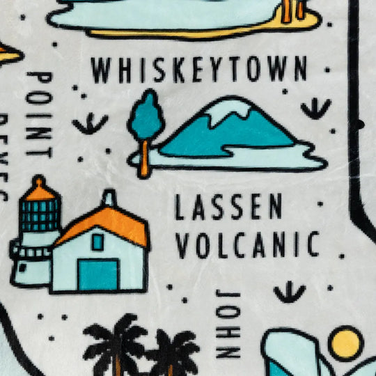 Fleece blanket with illustrations of a mountain, house, and text about Whiskeytown and Lassen Volcanic National Park.