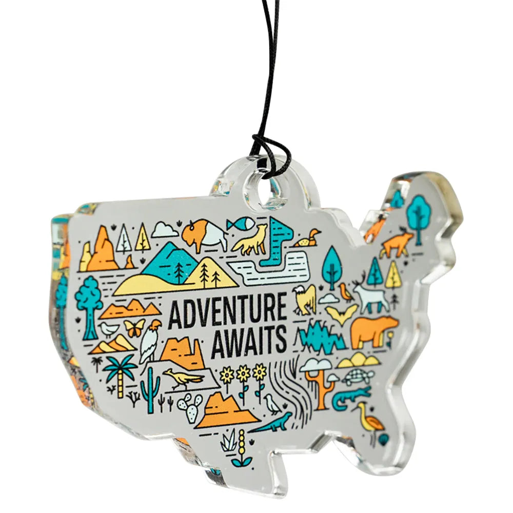 USA map-shaped ornament with 'Adventure Awaits' text and nature illustrations on a white background.
