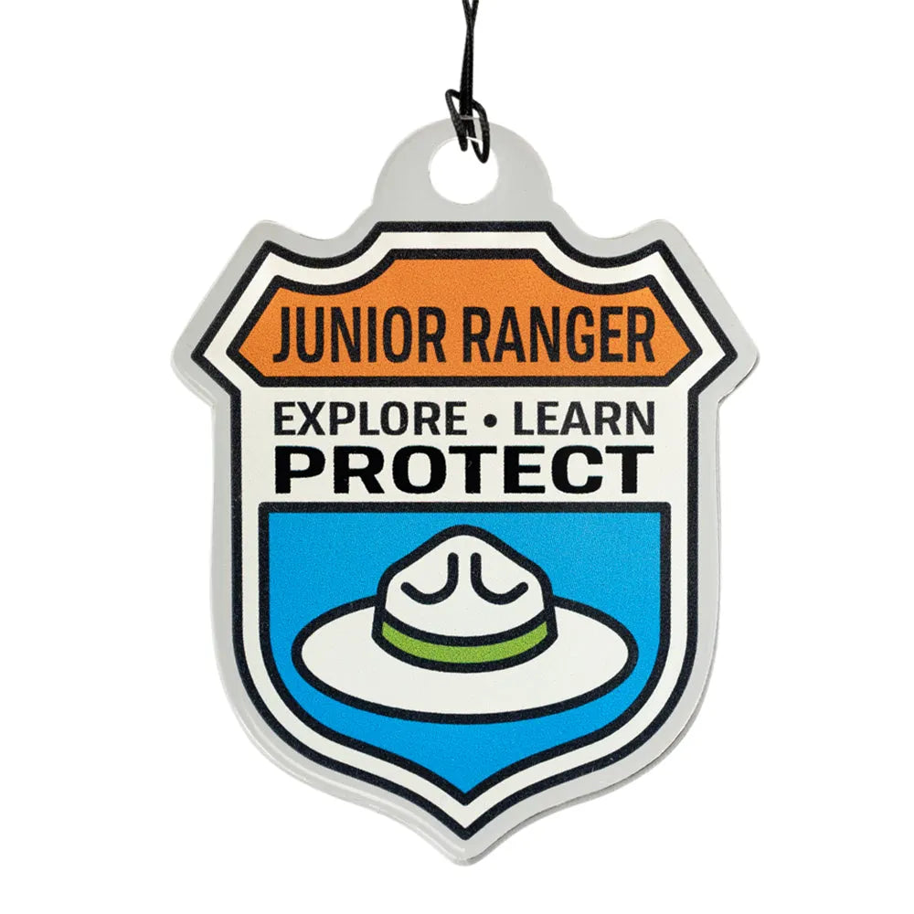 Junior Ranger badge shaped ornament with text 'Explore, Learn, Protect' and an image of the flat-rimmed National Park Service hat on a white background
