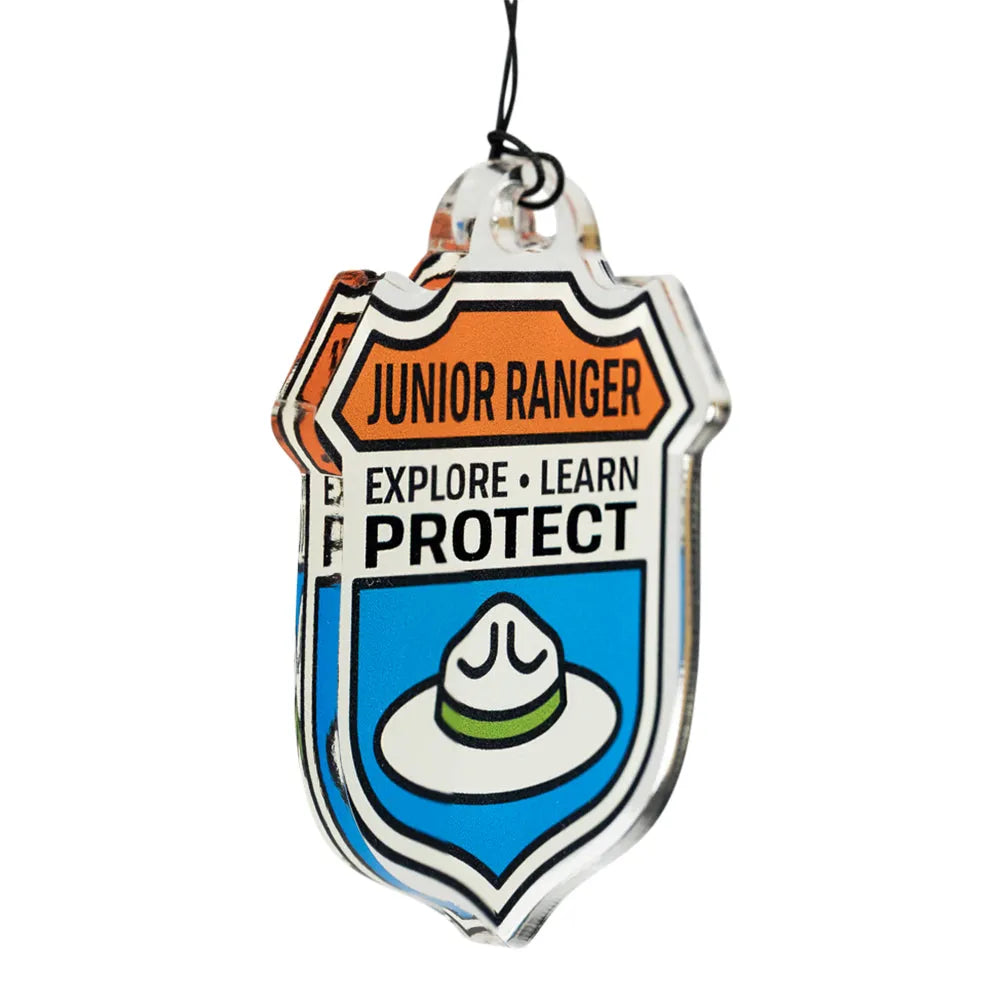 Junior Ranger badge shaped ornament with text 'Explore, Learn, Protect' and an image of the flat-rimmed National Park Service hat on a white background