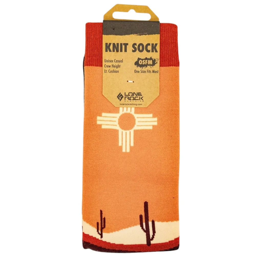 Packaged orange knit sock with desert design and a Zia Sun against a white background