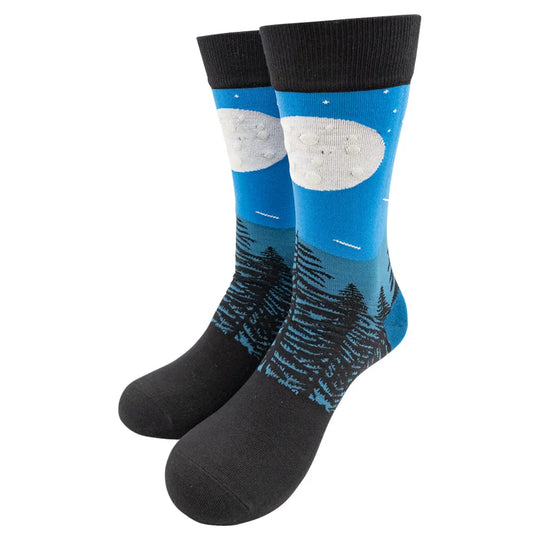 Pair of socks with a full moon rising over a forest design on a white background
