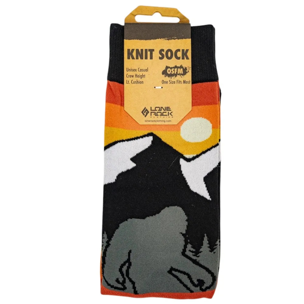 Knit sock with mountain design background and a silhouette of Bigfoot in the foreground in packaging on a white background