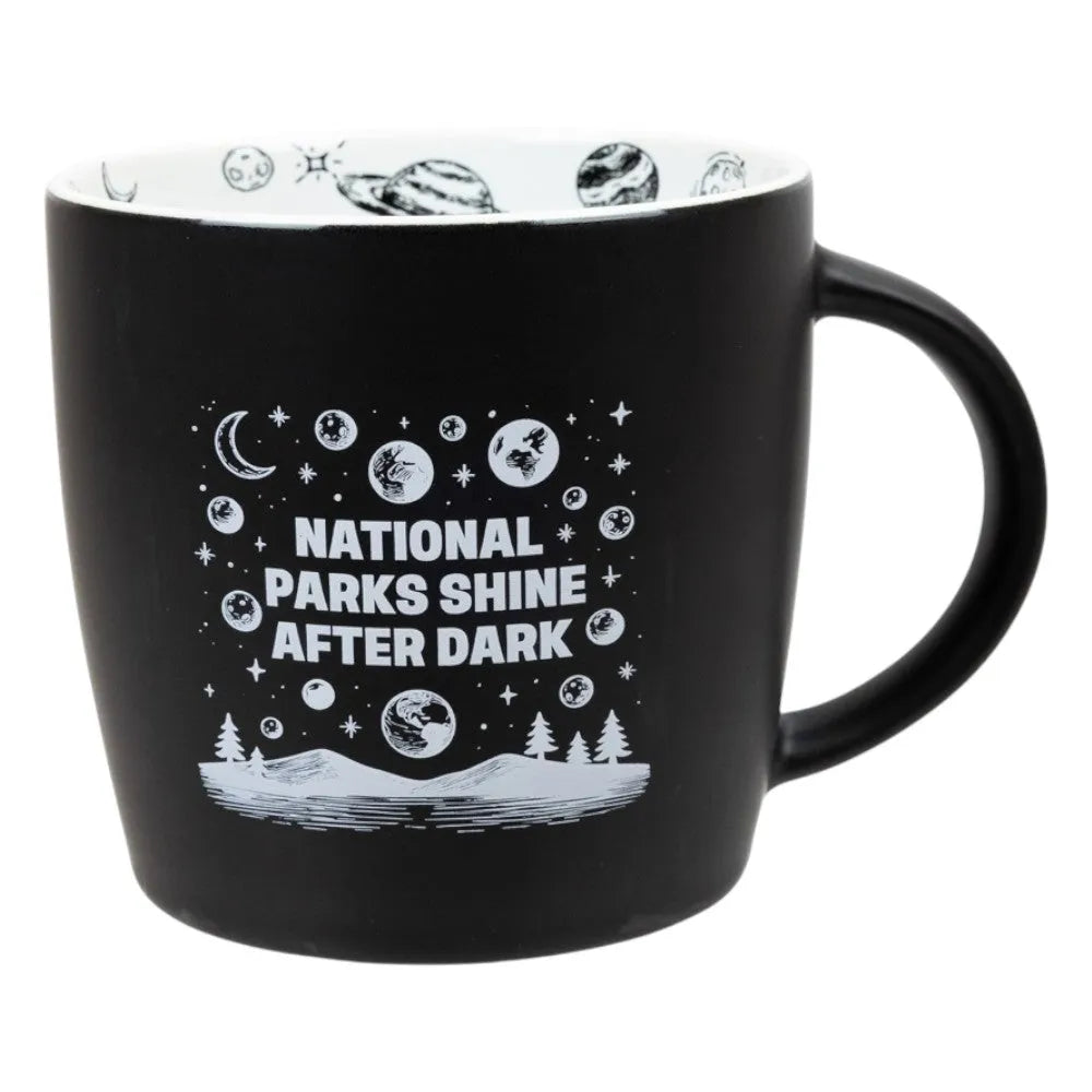 Black mug with white "National Parks Shine After Dark" graphic design and text on a white background