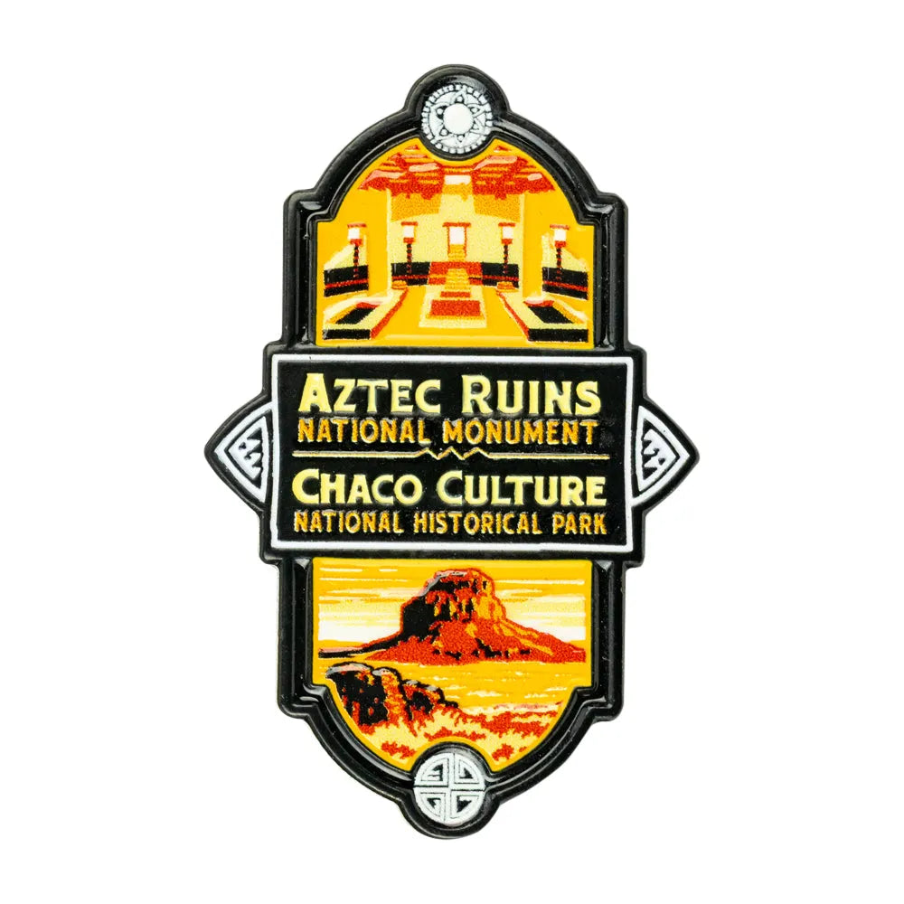 A vintage-style enamel pin or featuring Aztec Ruins National Monument and Chaco Culture National Historical Park graphics, with a black border and yellow, orange, and red illustrated scenes on a white background.