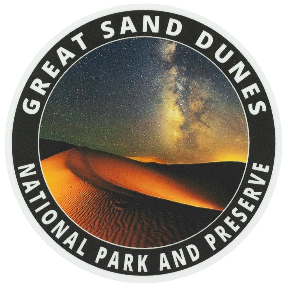 A circular sticker or decal featuring a desert night scene with glowing sand dunes under a starry sky and the Milky Way, surrounded by a black border with white text reading &