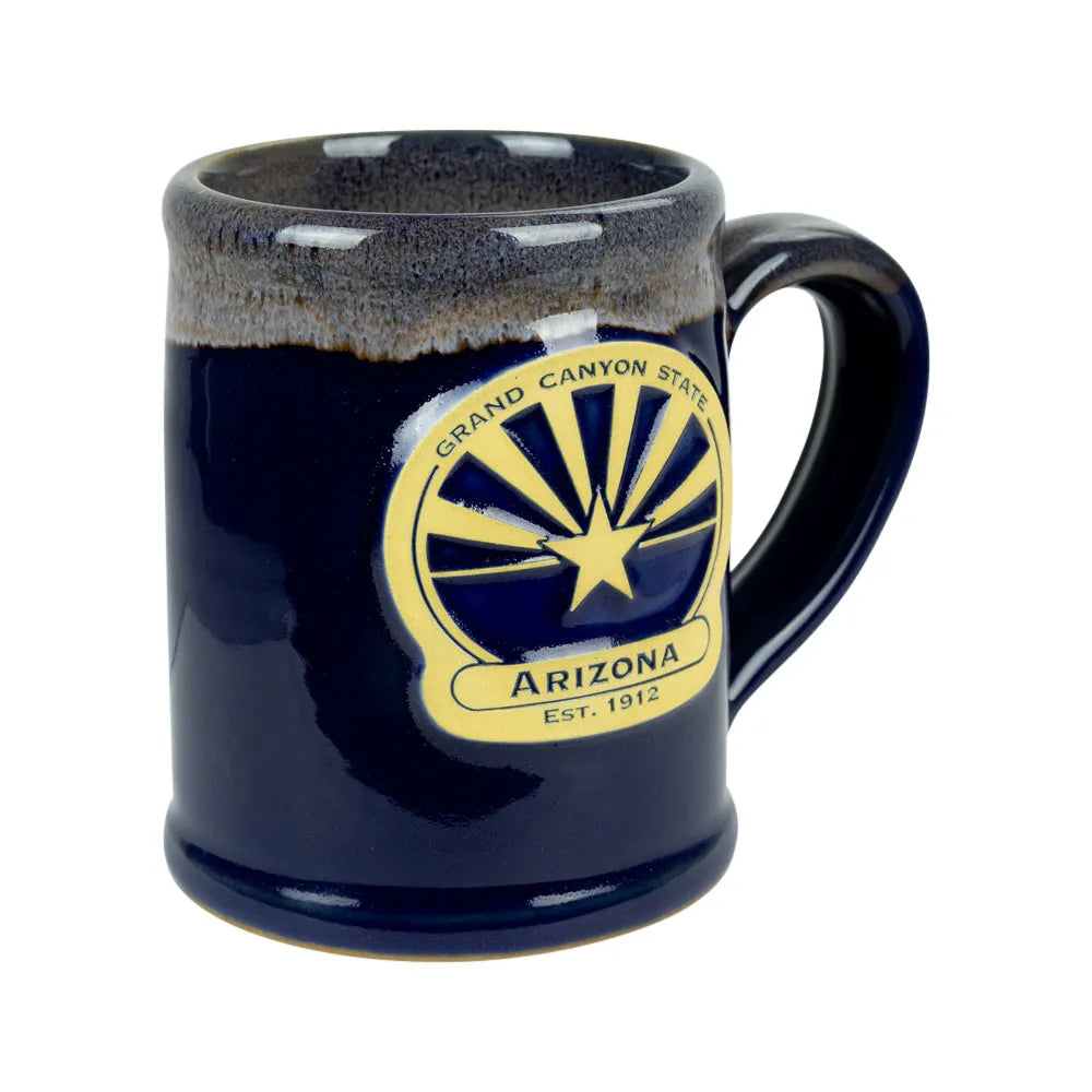 A dark blue glazed ceramic mug featuring a gold and navy blue &