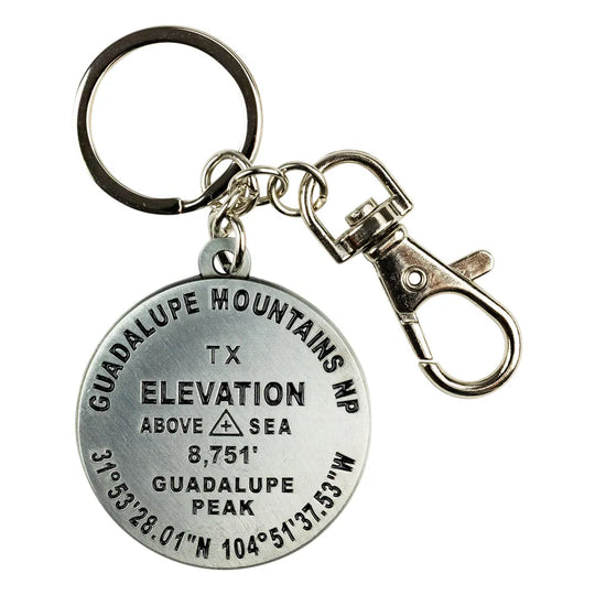 A silver-toned metal keychain featuring a round engraved pendant with elevation and geographic details for Guadalupe Mountains NP, TX, attached to a split ring and lobster clasp on a white background.