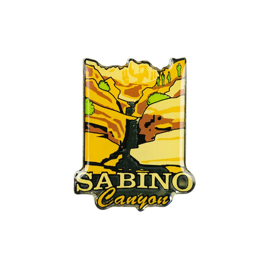 A Sabino Canyon photo dome pin featuring a stylized canyon landscape with yellow and orange rock formations, green trees, and the text &