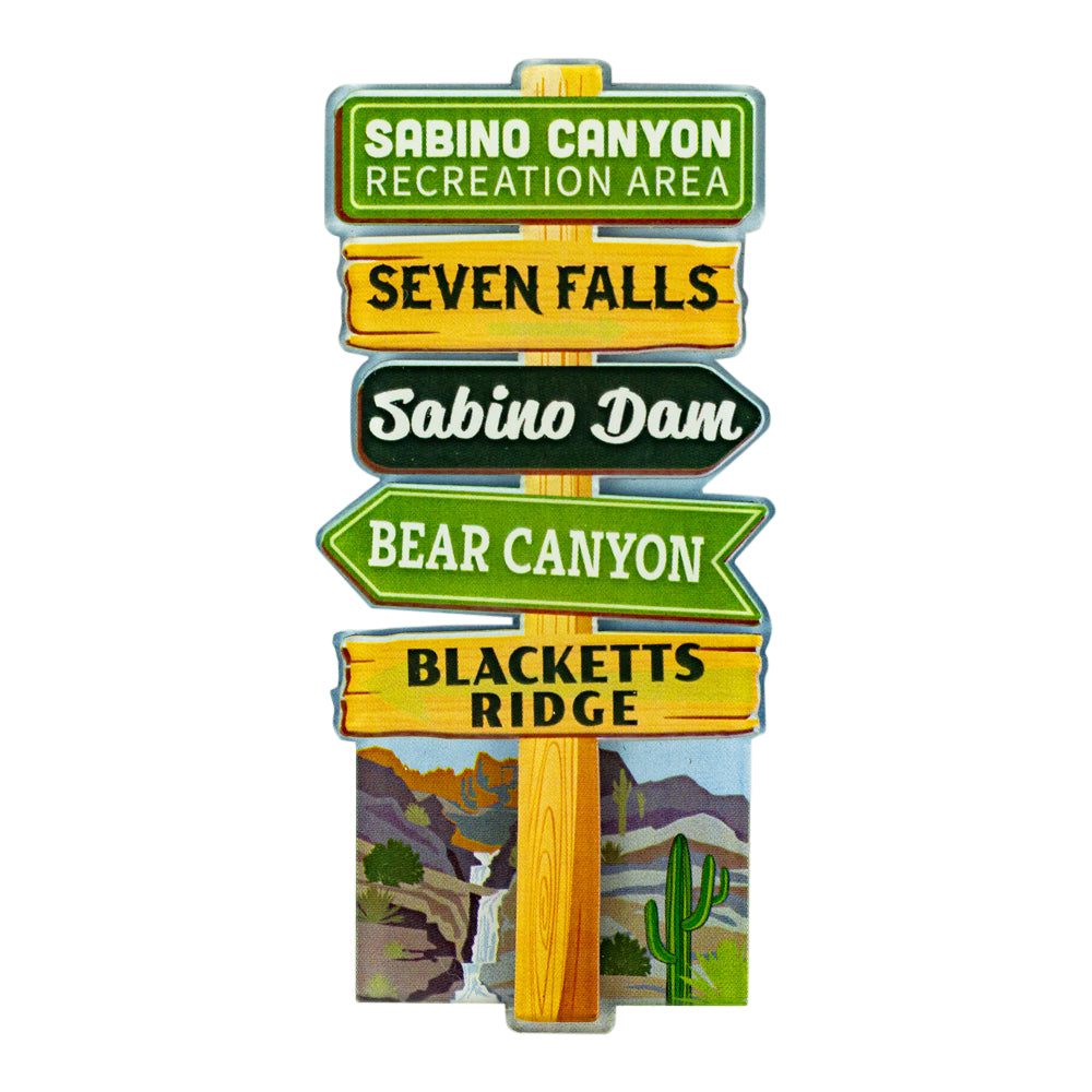 An acrylic magnet depicting a vertical wooden signpost featuring multiple directional signs for Sabino Canyon Recreation Area, Seven Falls, Sabino Dam, Bear Canyon, and Blacketts Ridge, with a small desert landscape illustration at the bottom, shown on a plain white background.