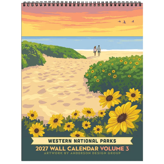 A spiral-bound 2027 Western National Parks wall calendar cover featuring a stylized beach scene with sunflowers, green shrubs, a sandy path, two people walking at the shoreline, and an orange sunset sky.