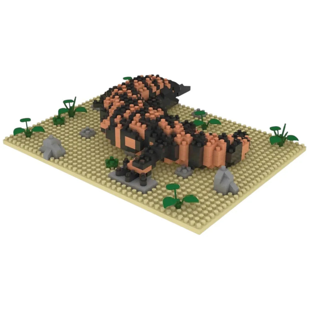 Toy gila monster model made from interlocking bricks on a beige baseplate with small plants and rocks.