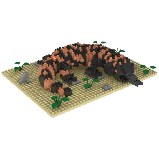 Model of a gila monster made from interlocking bricks on a beige base with green plants.
