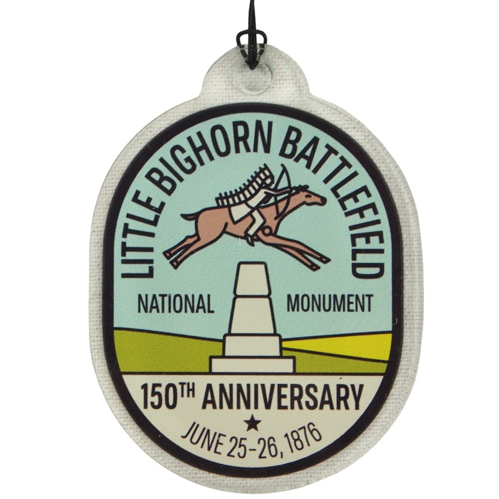 Oval badge ornament with Little Bighorn Battlefield National Monument branding and anniversary details.