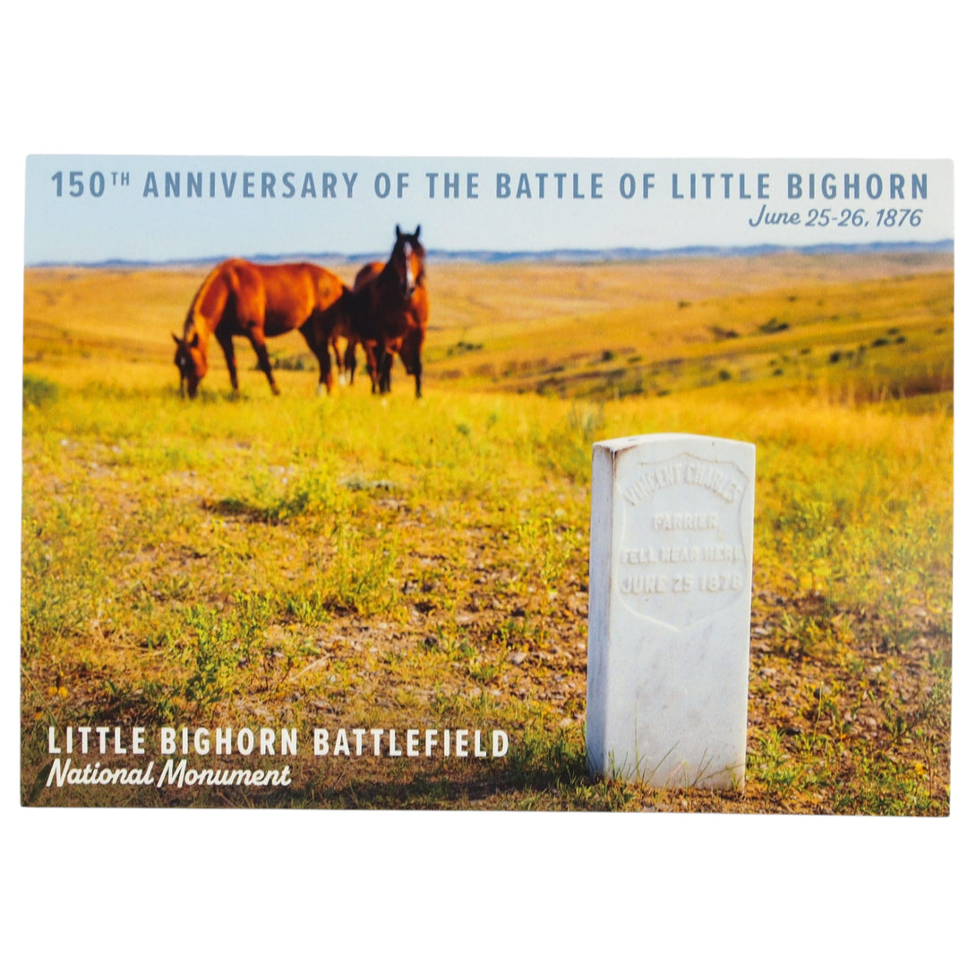 Two horses grazing in a field with a monument and text about the 150th anniversary of the Battle of Little Bighorn.