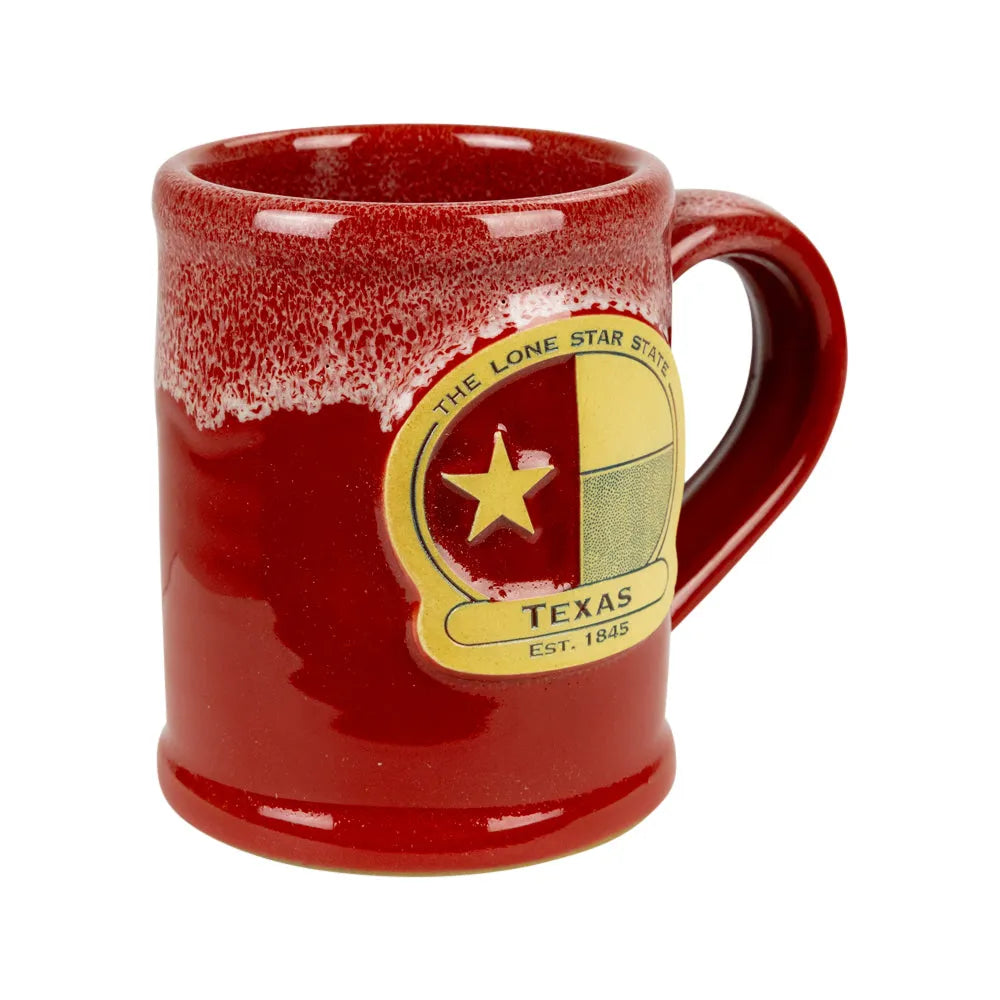 A red ceramic mug with a textured, speckled glaze around the rim and handle, featuring a gold and yellow Texas state emblem on the side.