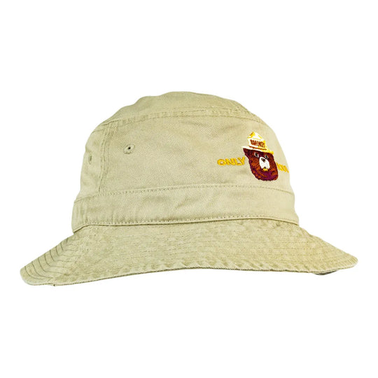 A light beige bucket hat with a small embroidered logo on the front featuring Smokey Bear.