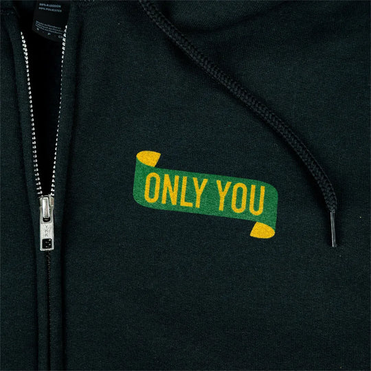 Close-up of a zip-up hoodie with a green and yellow embroidered graphic on the chest that reads &