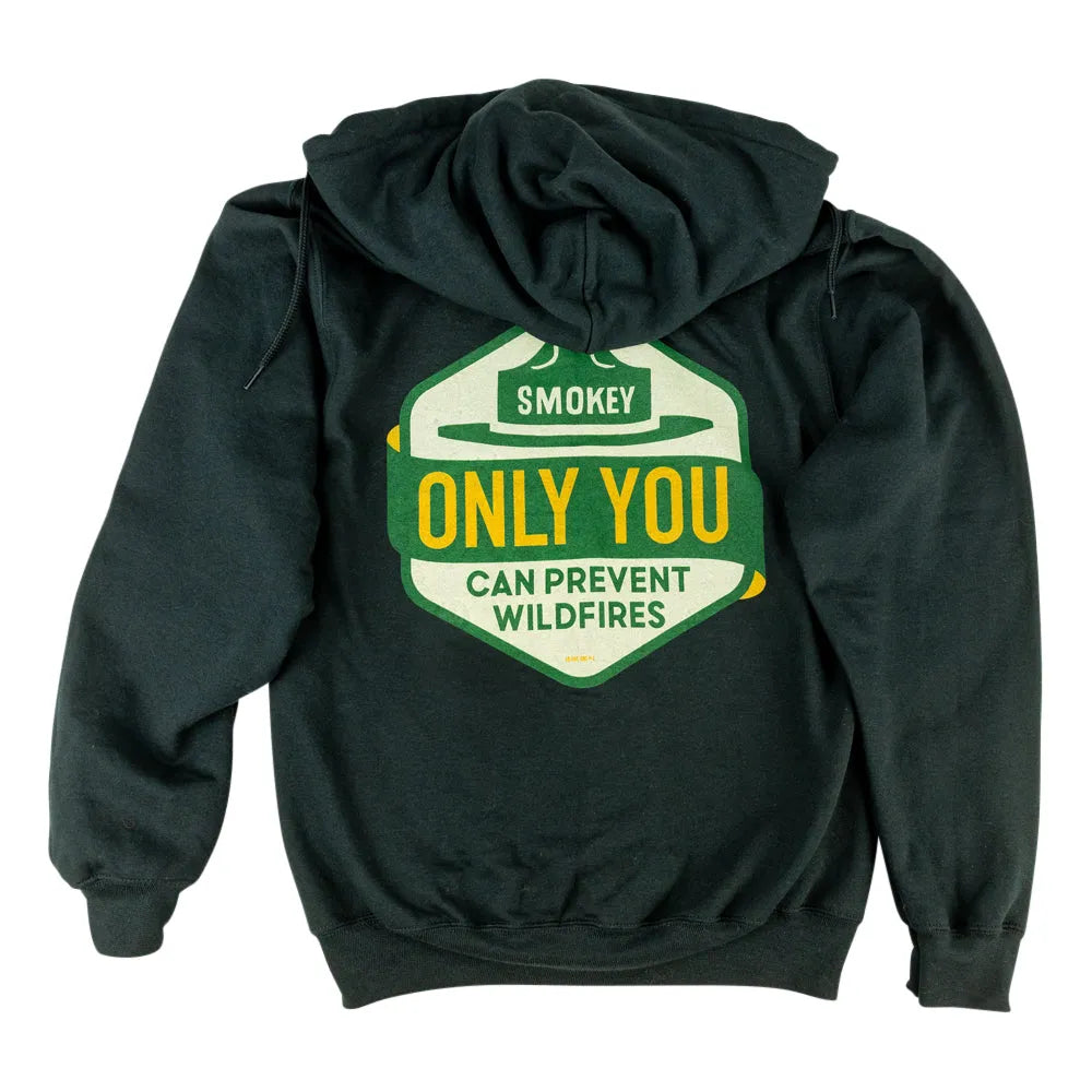A dark hoodie shown from the back, featuring a large graphic print of a shield-shaped badge with a cowboy hat and the text &