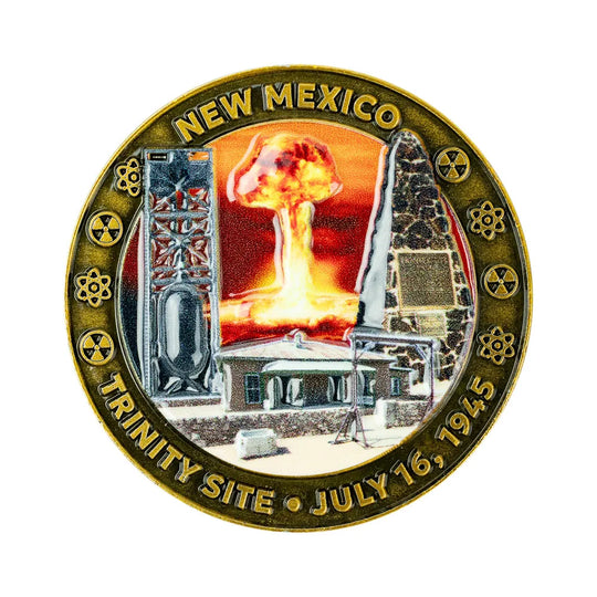 A circular commemorative coin or medallion for the Trinity Site in New Mexico, dated July 16, 1945. The design shows a nuclear explosion mushroom cloud between two tall structures, with surrounding text reading “NEW MEXICO” and “TRINITY SITE • JULY 16, 1945.