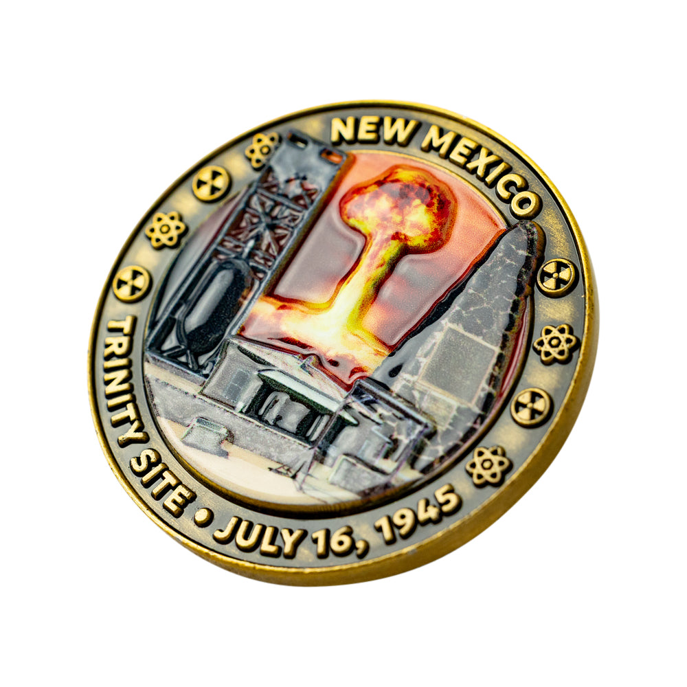 A circular commemorative coin  featuring a nuclear explosion scene with the text &