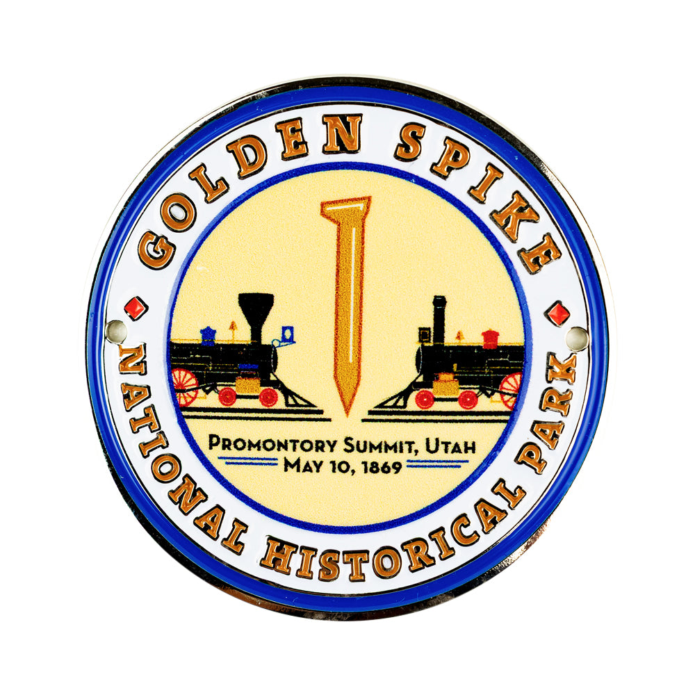 A circular medallion for Golden Spike National Historical Park, featuring a vintage design with two steam locomotives, a large gold spike in the center, and text reading &