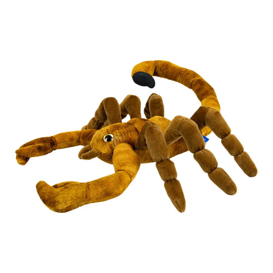 A plush toy scorpion in a warm golden-brown color, featuring a segmented body, articulated legs, a curved tail with a black tip, and a small embroidered eye, shown on a plain white background.