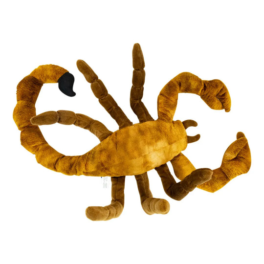 A plush toy scorpion in a warm golden-brown color, shown from the bottom up, featuring a segmented body, articulated legs, a curved tail with a black tip, shown on a plain white background.