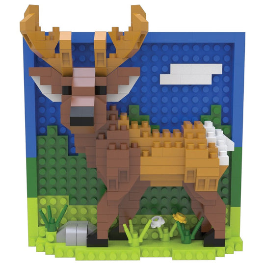 A block-style toy deer model built from interlocking bricks, shown against a blue sky backdrop with green grass and small flowers at the base. No person, animal, or real environment is present, so this is Product/Packaging rather than Lifestyle or Scenery.