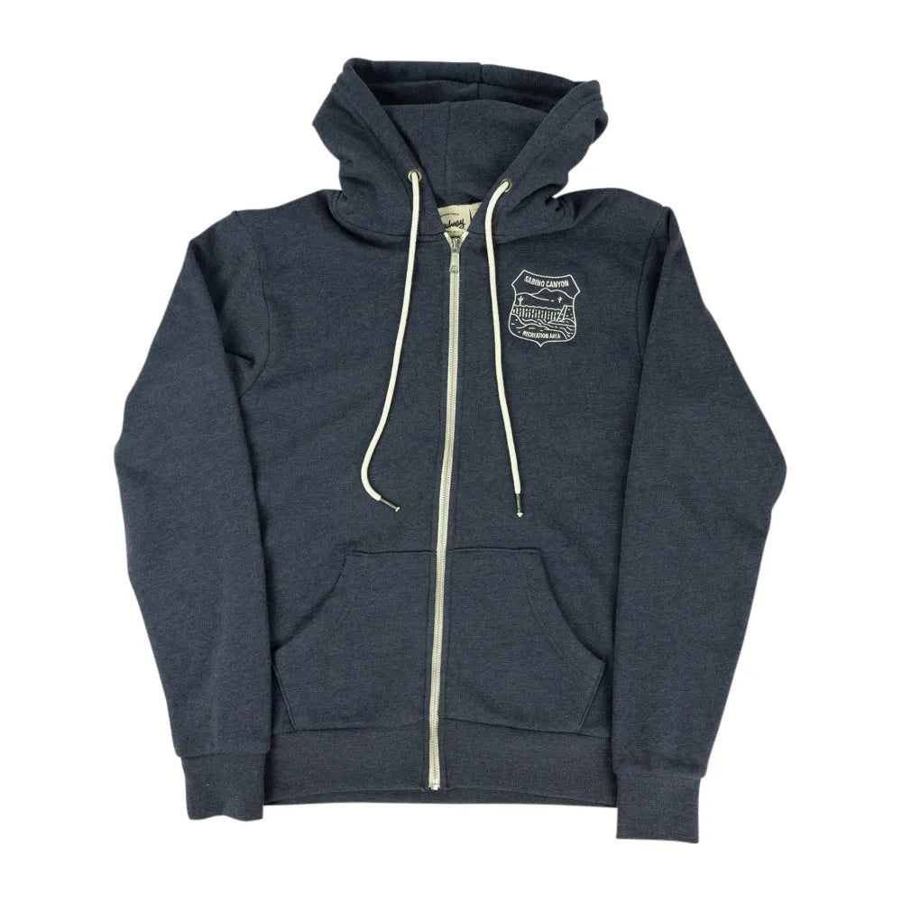 A dark heather gray zip-up hoodie with cream-colored drawstrings and a zipper, featuring a small embroidered shield logo on the left chest, displayed against a solid white background.
