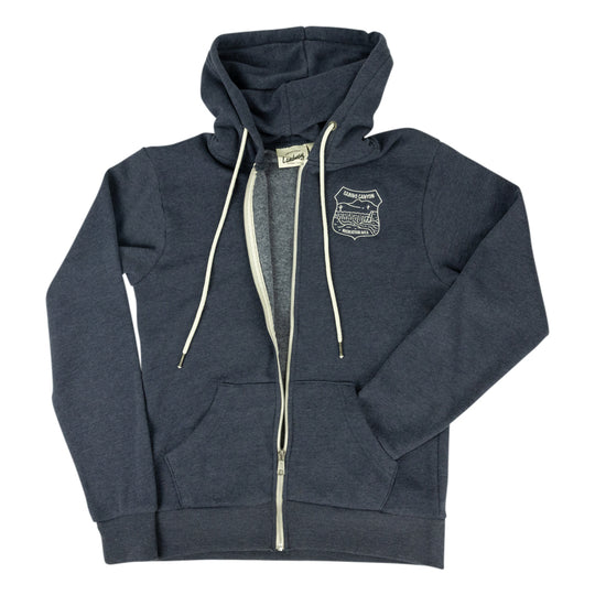A navy blue zip-up hoodie with cream-colored drawstrings and a silver zipper, featuring shield embroidery on the left chest. The hoodie is laid flat against a solid white background.