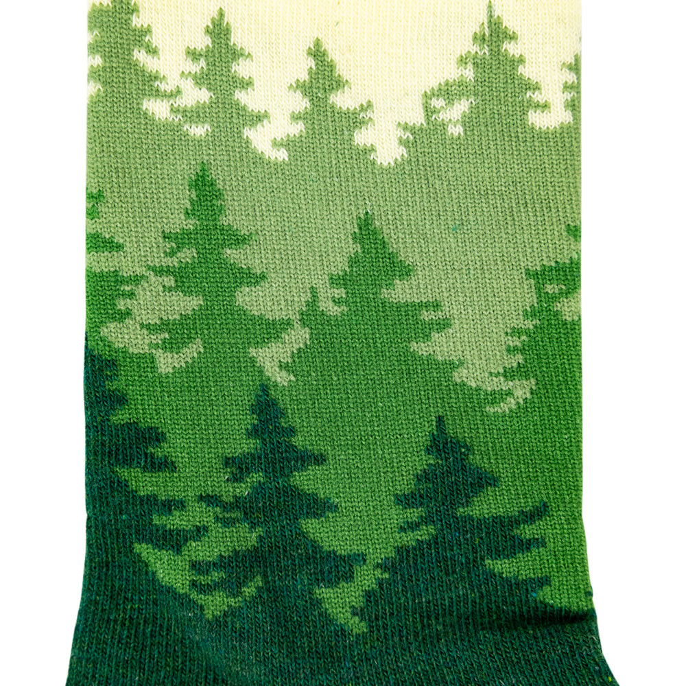 A close-up of a knit sock featuring a green pine forest pattern with a cream-colored top section, set against a plain white background.