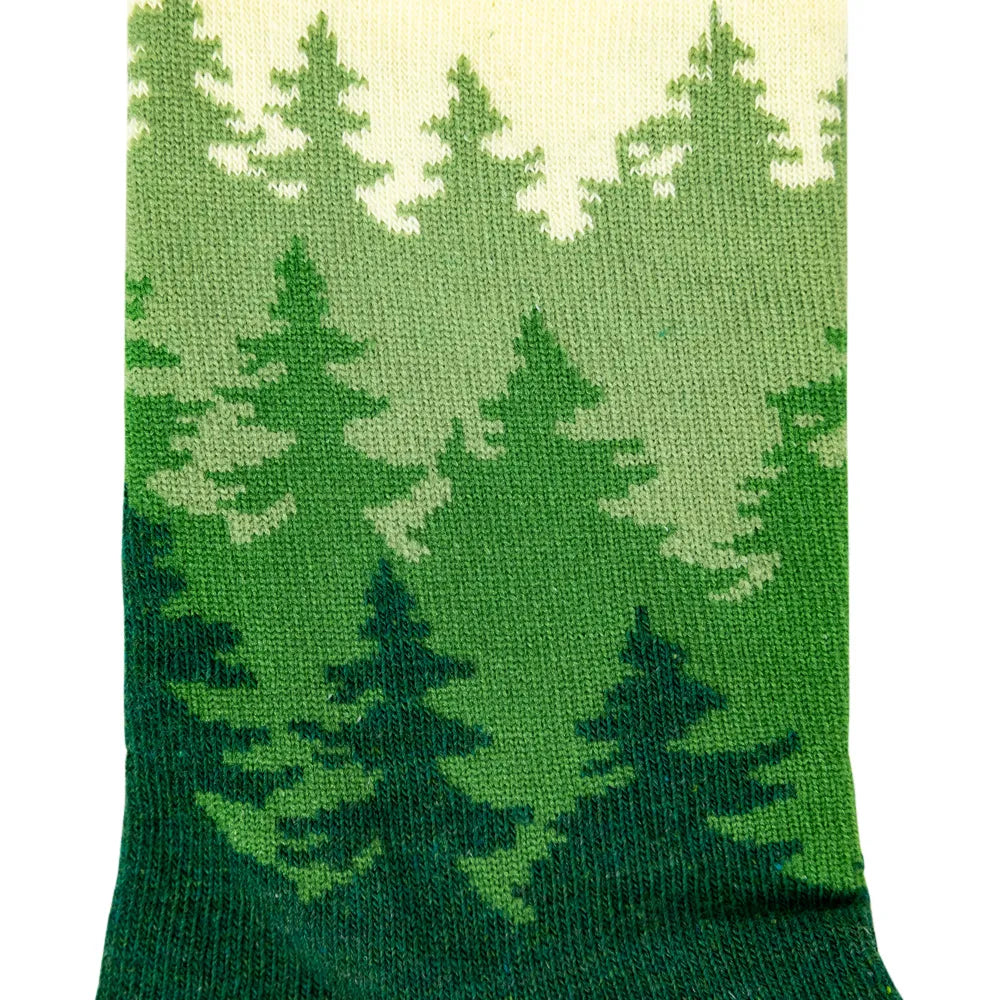 A close-up of a knit sock featuring a green pine forest pattern with a cream-colored top section, set against a plain white background.
