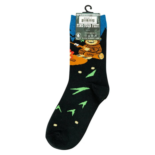 novelty crew sock on a hanger against a plain white background. The sock is primarily black with a colorful cartoon bear illustration in orange, brown, and green, along with small green arrow-like shapes and beige dots.