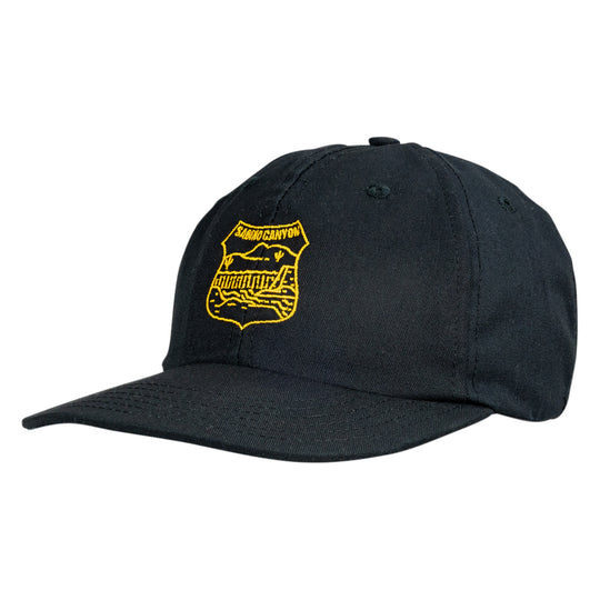 A black baseball cap featuring a yellow embroidered shield-shaped badge on the front with the text &