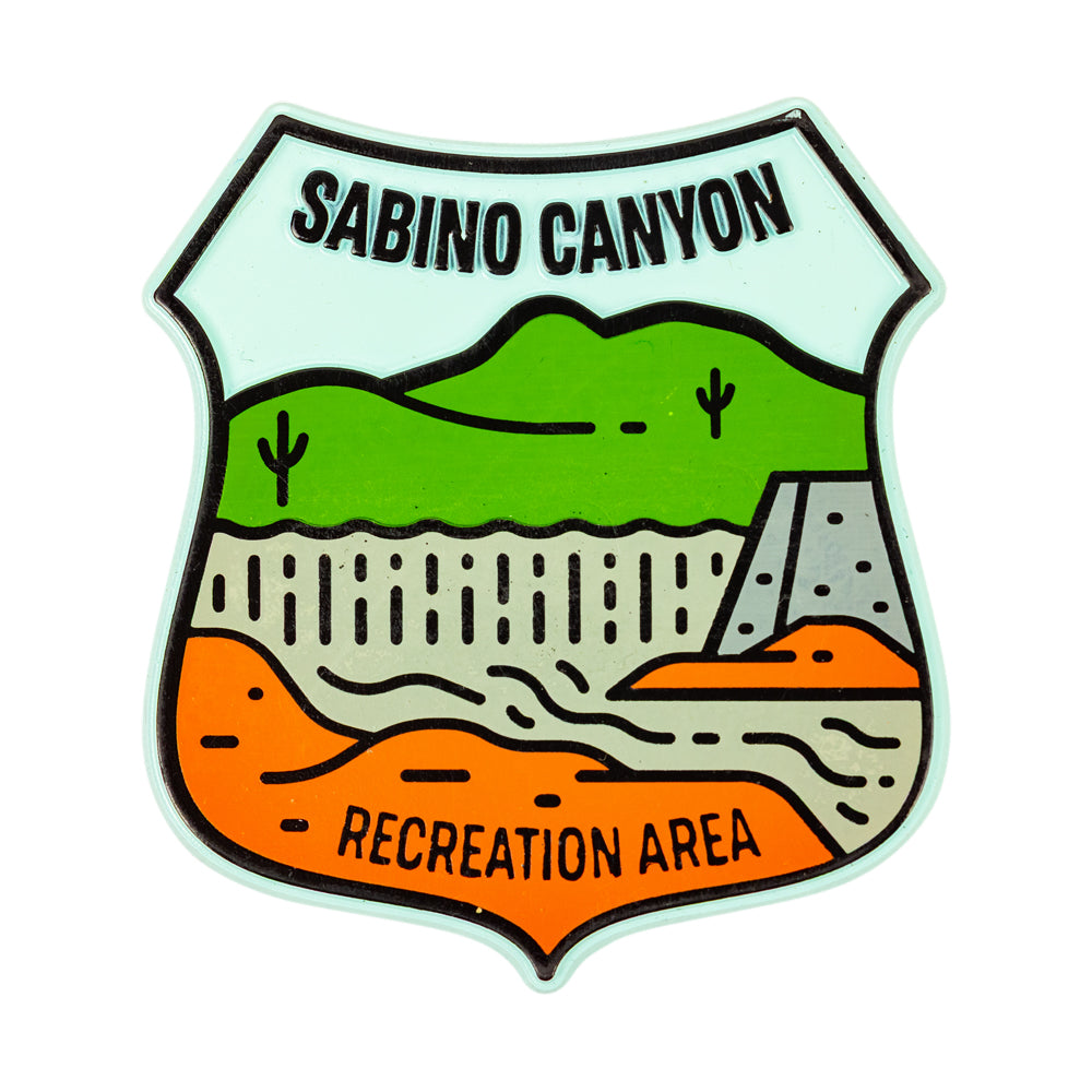 A shield-shaped rubber flex magnet featuring a stylized landscape labeled &