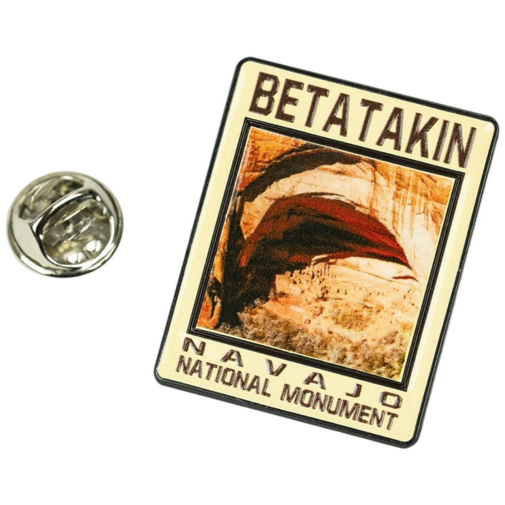A square enamel lapel pin featuring a desert canyon scene with the text &