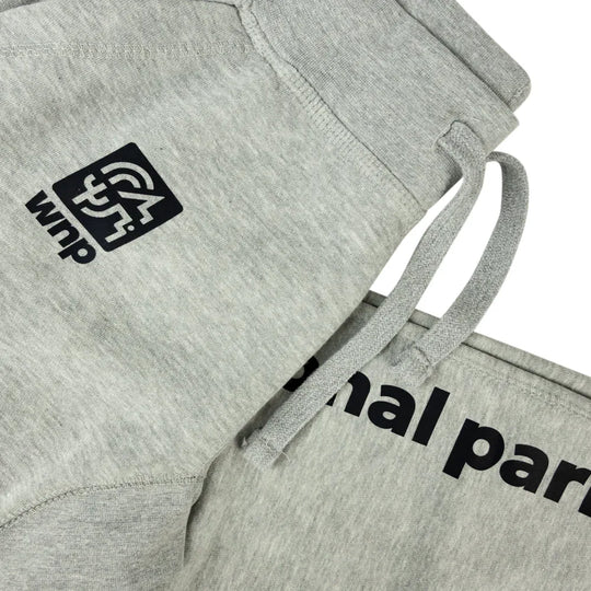 Close-up of light heather gray sweatpants with black printed branding and partial text on the leg, plus matching drawstrings and a ribbed waistband, shown on a white background.
