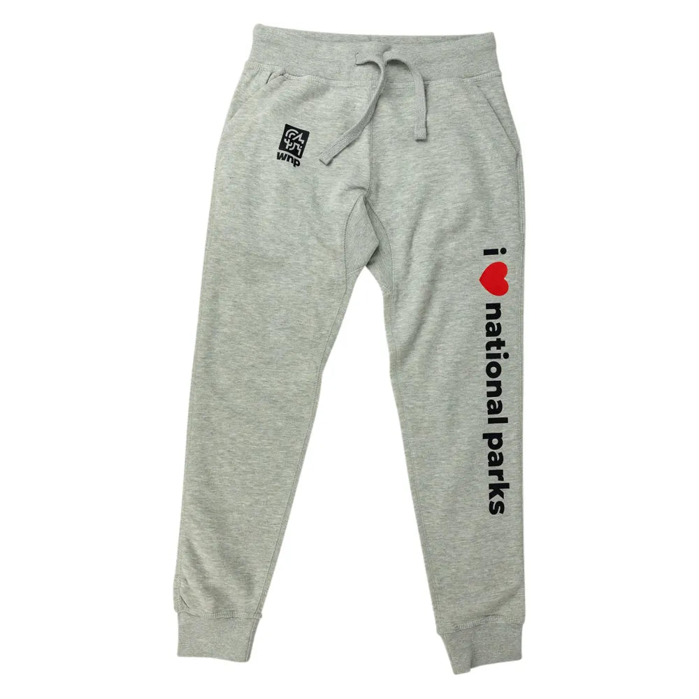 Light heather gray sweatpants with a drawstring waist, featuring a black square logo patch on the left thigh and vertical black text reading 'i <heart> national parks' with a red heart on the right leg.