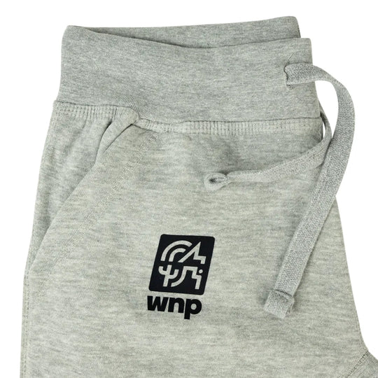 Close-up of light heather gray sweatpants with a black square logo patch on the front pocket and a matching gray drawstring, shown on a white background.