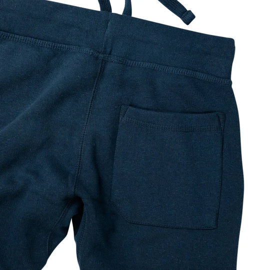 Close-up of the back waistband and pocket of dark navy blue sweatpants, showing the fabric texture and stitching against a white background.