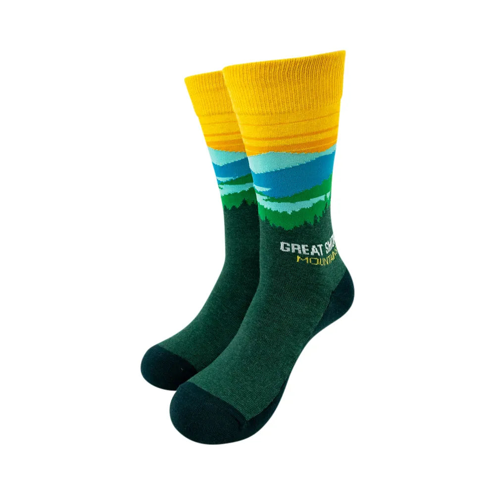 A pair of crew socks with a yellow ribbed cuff, a blue and green landscape graphic, and the text 'GREAT SMOKY MOUNTAINS' on a dark green foot.