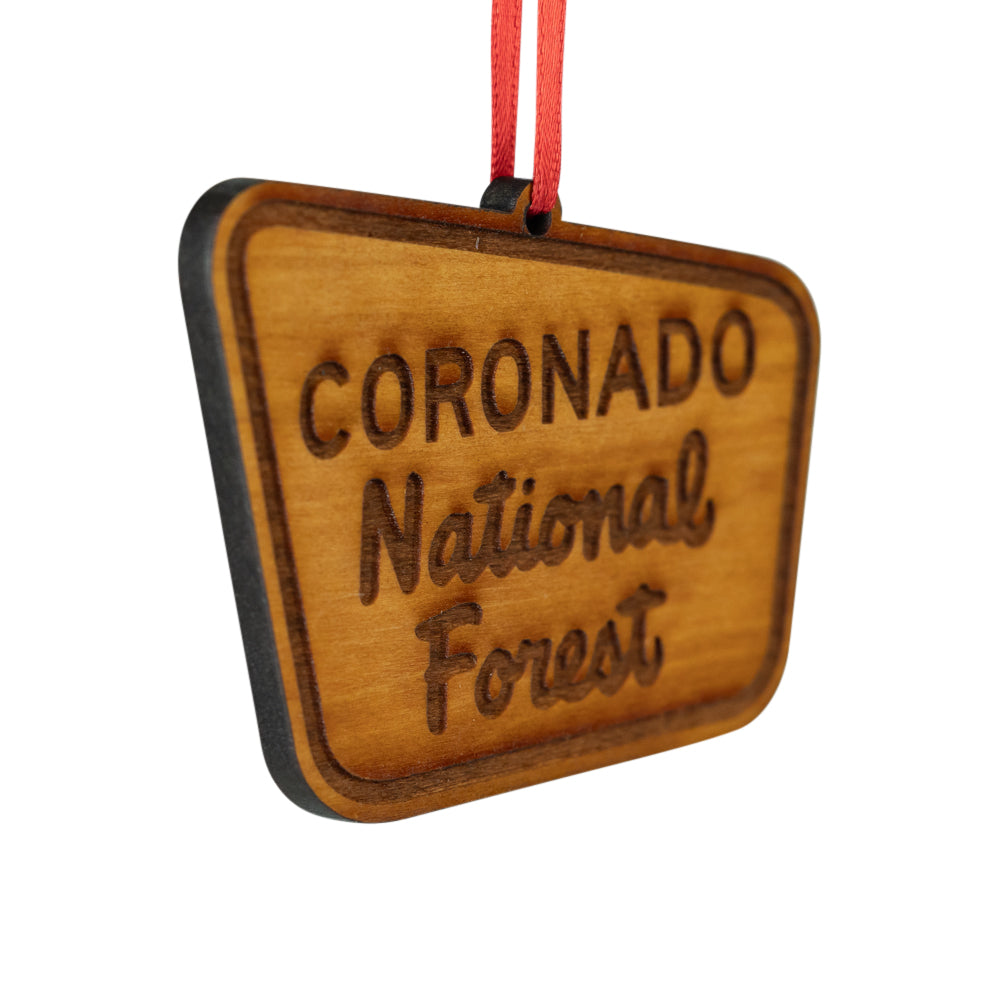 A wooden Coronado National Forest ornament with a red hanging ribbon, shown on a plain white background.