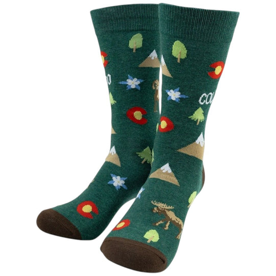 A pair of dark green crew socks with a colorful outdoor pattern featuring mountains, trees, flowers, a moose, and Colorado state symbols, shown on a plain white background.