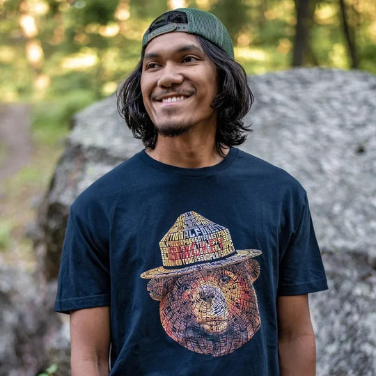 Man wearing a navy blue t-shirt with the Smokey Bear typography graphic on the front.