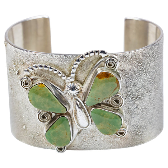 Silver cuff bracelet with green stone butterfly design on a white background