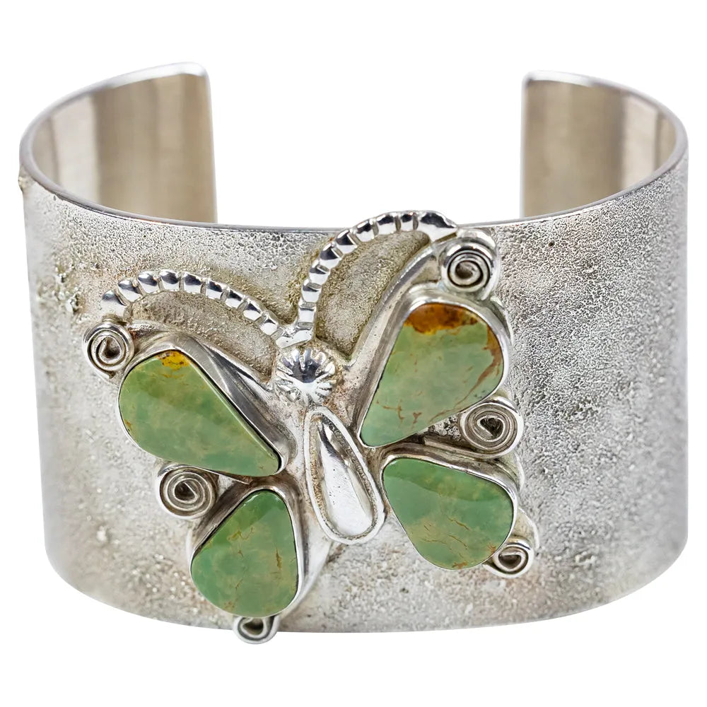 Silver cuff bracelet with green stone butterfly design on a white background